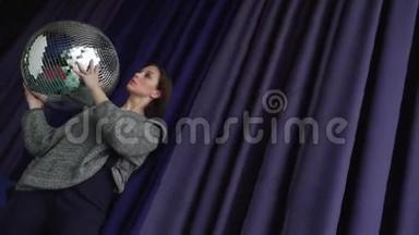 一个灰色的漂亮女孩手里拿着一个大迪斯科球